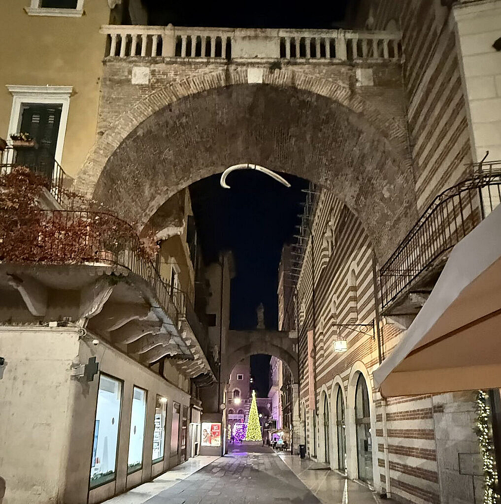 Arco della Costa en Verona iluminado de noche con árbol navideño