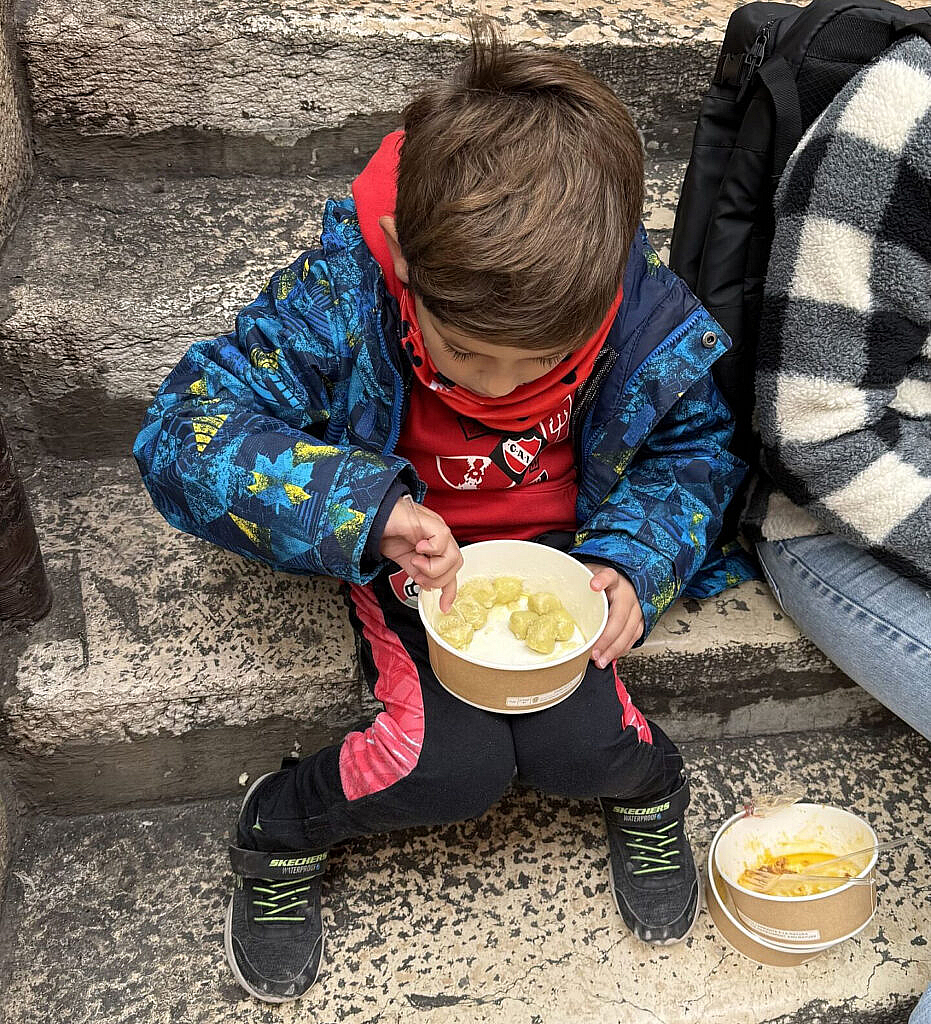 Vicente comiendo pasta sentado en escalones de la calle en Verona
