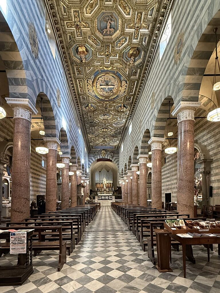 Interior del Duomo de Volterra con piso ajedrezado y techo dorado