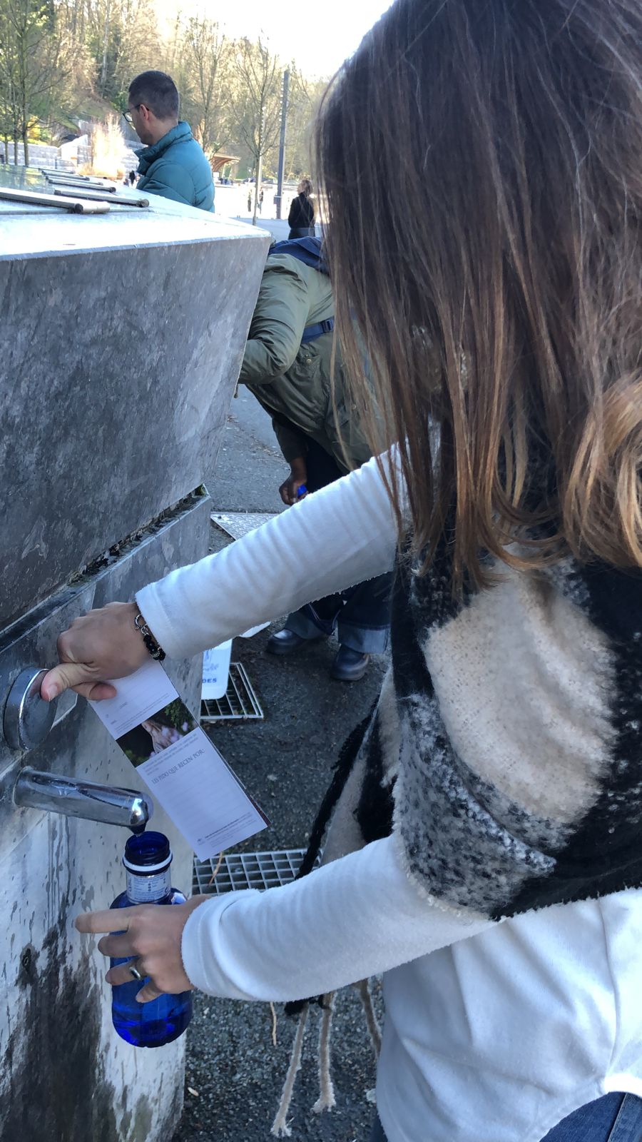 Llenando una botella con agua del santuario de Lourdes