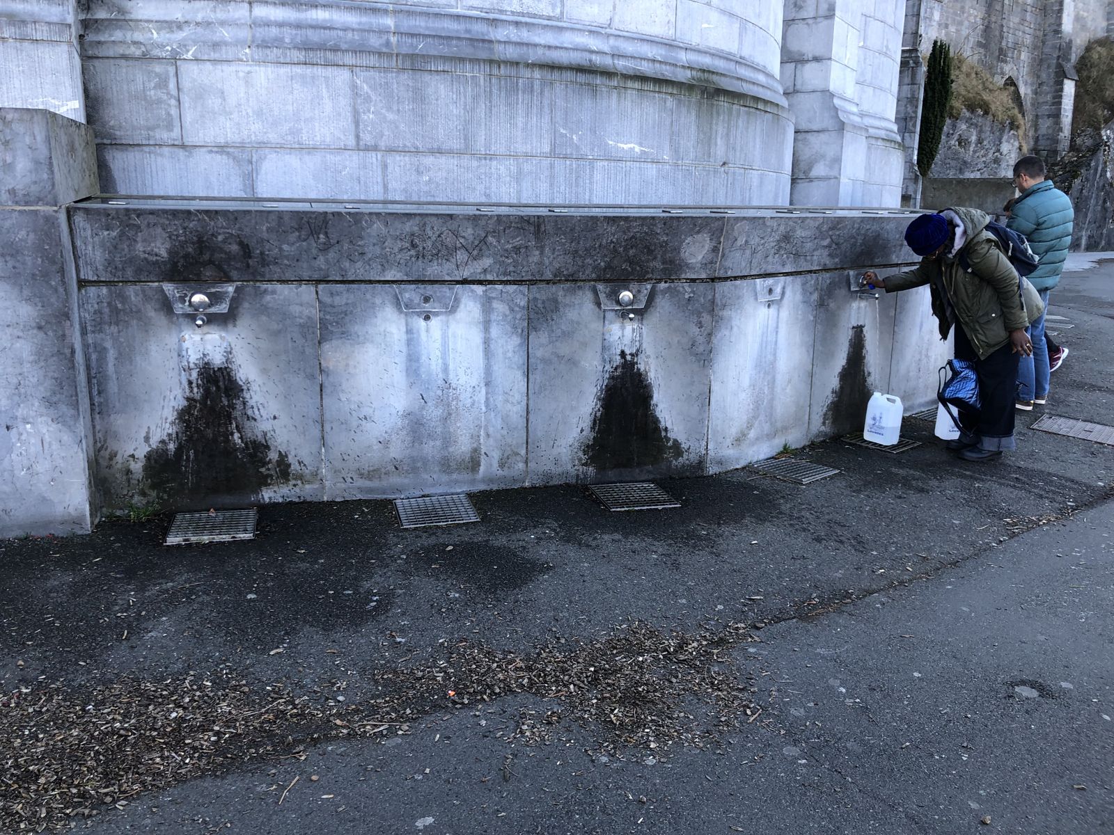 Las canillas de agua del santuario de Lourdes, con peregrinos llenando bidones