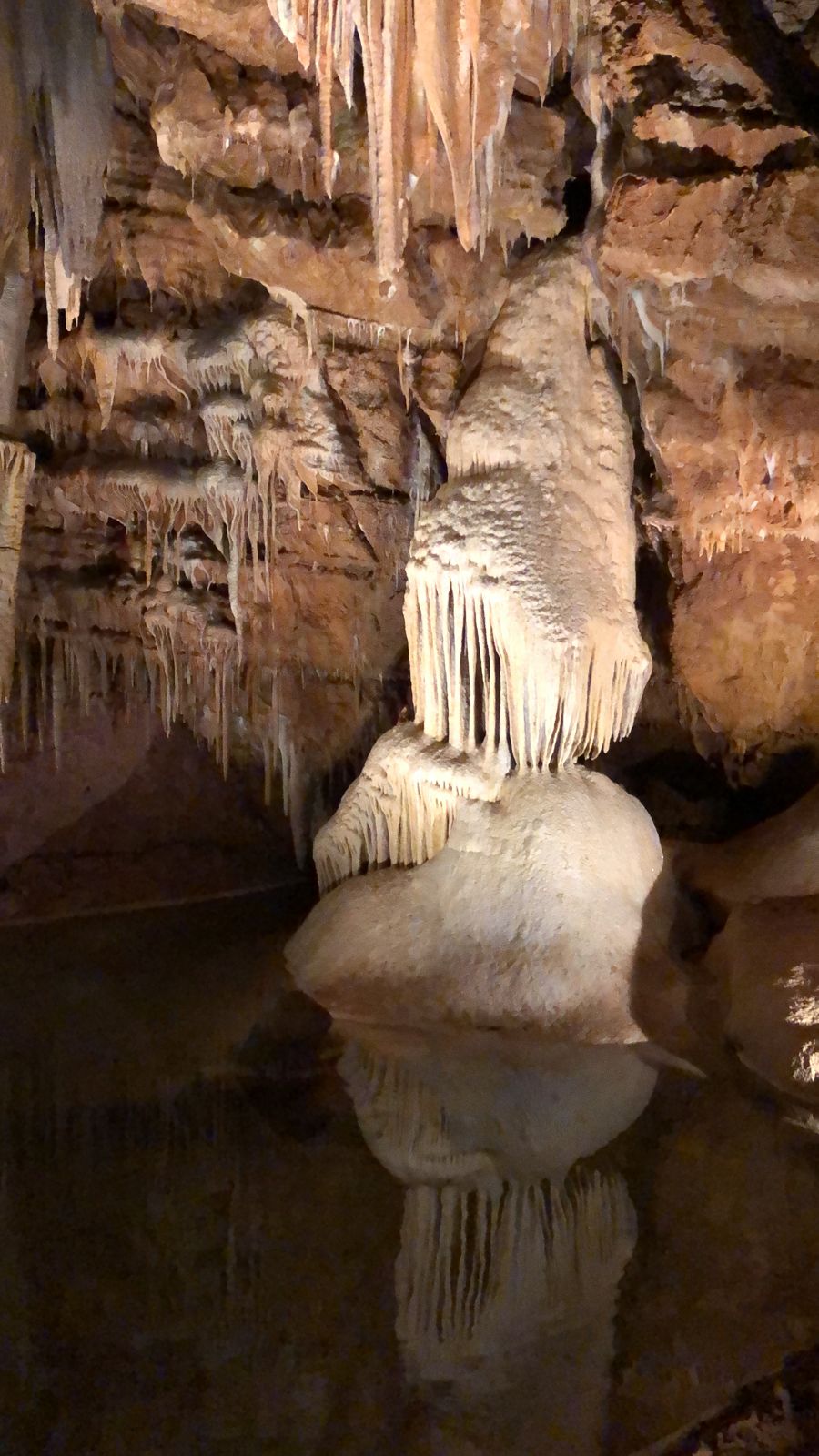 Columna de estalactitas reflejada en el agua de la gruta