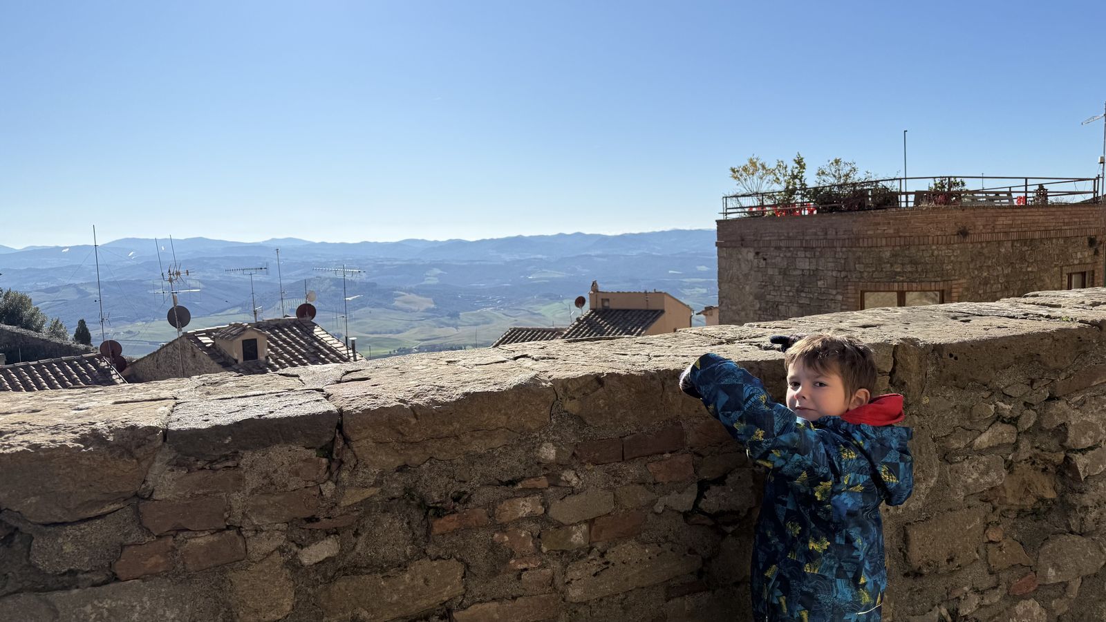 Vicente asomado a la muralla de un pueblo toscano, mirando los techos y las colinas