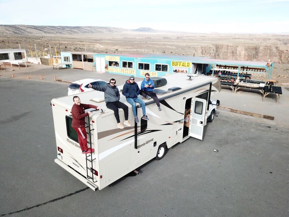 Los cuatro amigos sentados arriba del techo del motorhome, en un trading post de ruta