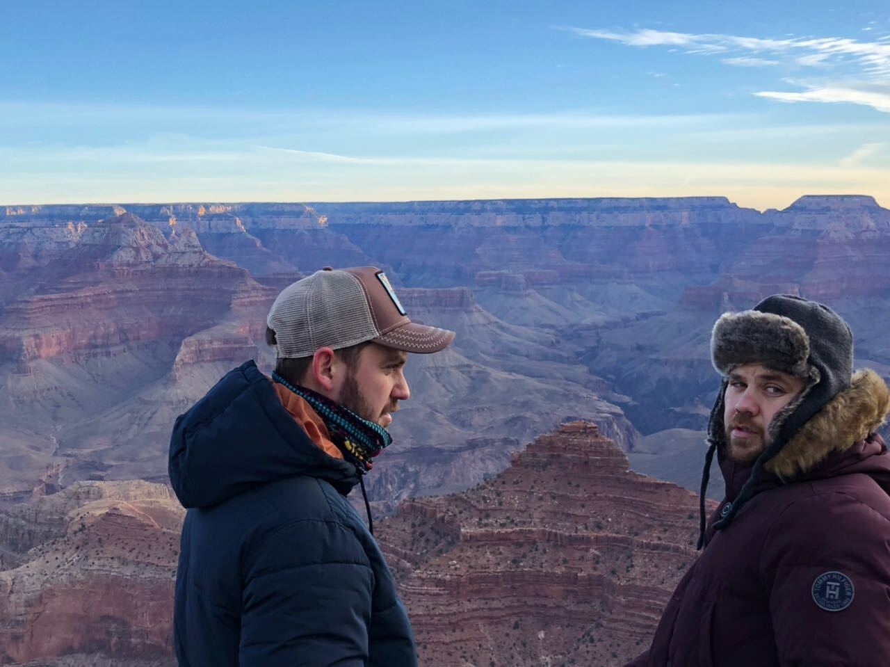 Dos de los amigos en el borde del Gran Cañón, con las capas de roca de fondo